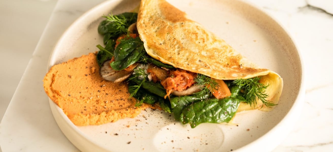 A well cooked omlette with spinach, mushrooms, meat, and herbs